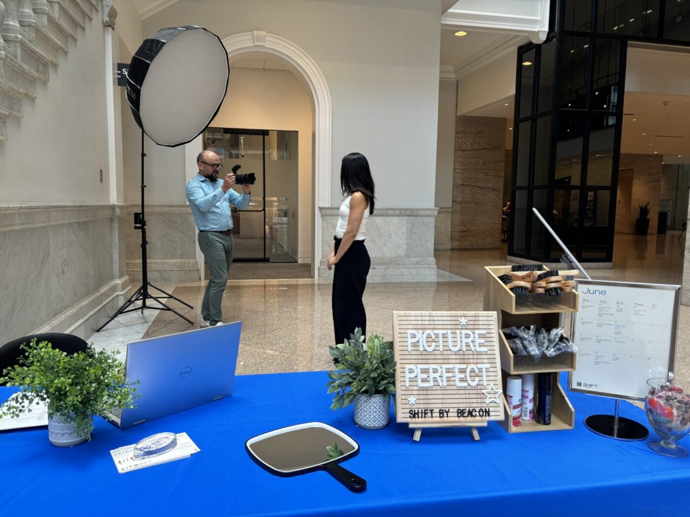 Woman in professional clothing has her headshot taken by photographer in office lobby