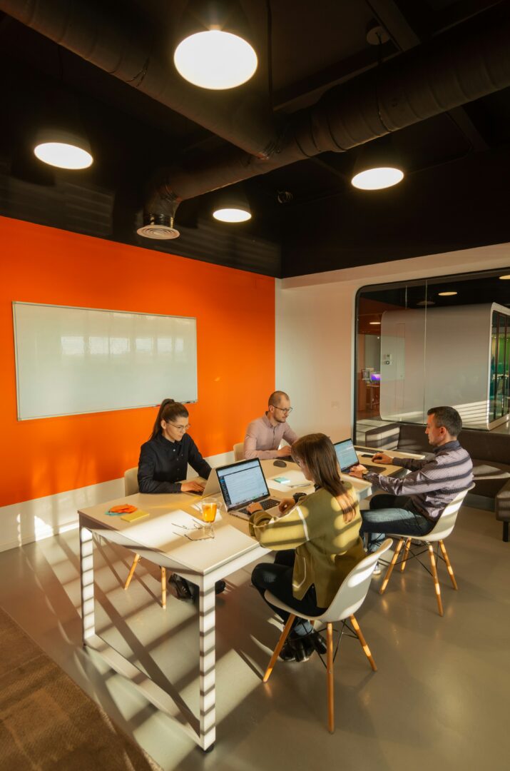 4 tenants sit in an office common area working on their computers