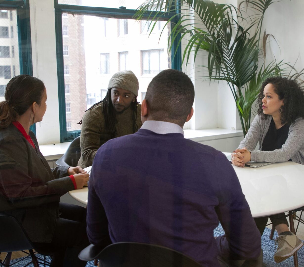 4 people sit at a small table in a conference room